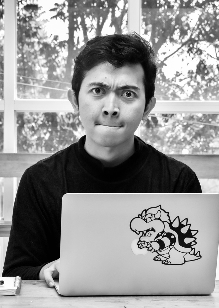 Ganis Angger Atmawarin, frowning at the camera over a laptop with a Bowser sticker